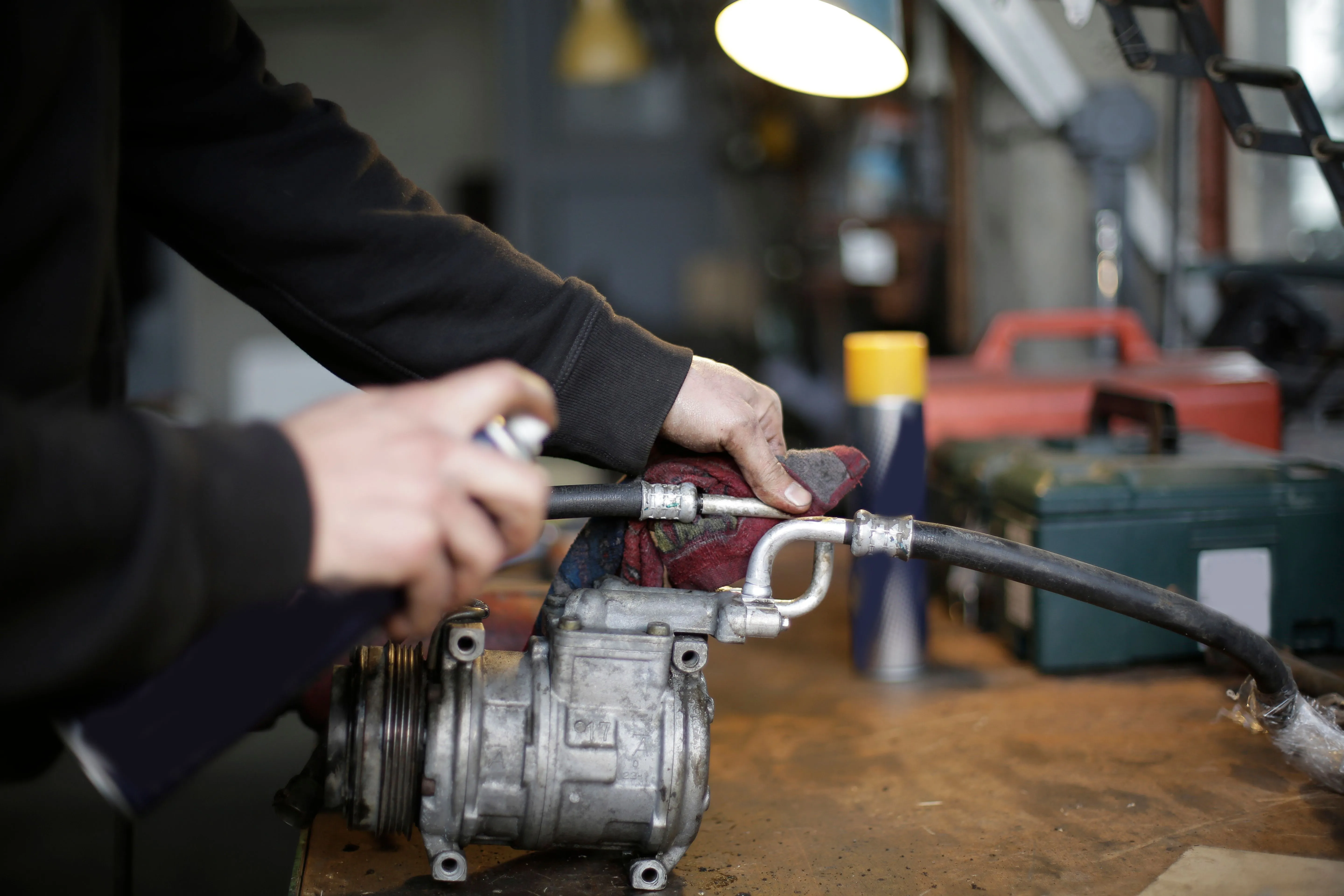 Technician cleaning an AC compressor on a workshop bench in Dubai